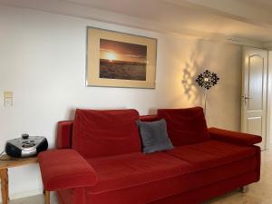 a red couch in a living room with a table at Nordlicht im Haus Kaya, Hafenstraße in Wyk auf Föhr