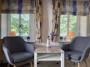 two chairs and a table in a room with windows at Nordlicht im Haus Kaya, Hafenstraße in Wyk auf Föhr