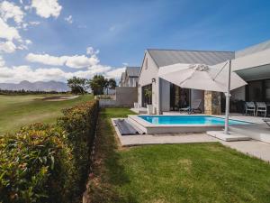 una casa con piscina y sombrilla en Moorlands Manor, en George