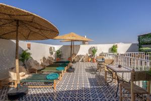 マラケシュにあるRiad Jabador De Marrakechのタイル張りの床に椅子とパラソルが置かれたパティオ