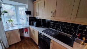 a kitchen with wooden cabinets and a sink and a dishwasher at Warm and Cosy 1 bed house in Chipping Norton in Chipping Norton