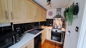 a kitchen with wooden cabinets and a stove top oven at Warm and Cosy 1 bed house in Chipping Norton in Chipping Norton