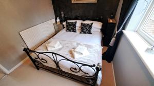 a small bed with black and white sheets and pillows at Warm and Cosy 1 bed house in Chipping Norton in Chipping Norton
