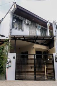 een huis met een hek ervoor bij Cozy Three-Bedroom Staycation House with Netflix, Wi-Fi, and Free Parking Garage near SM Caloocan in Manilla +23 foto's