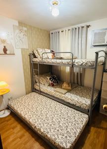 2 Etagenbetten in einem kleinen Zimmer mit Fenster in der Unterkunft Cozy Three-Bedroom Staycation House with Netflix, Wi-Fi, and Free Parking Garage near SM Caloocan in Manila