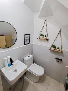 een badkamer met een toilet, een wastafel en een spiegel bij Cozy Three-Bedroom Staycation House with Netflix, Wi-Fi, and Free Parking Garage near SM Caloocan in Manilla