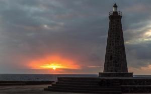 a lighthouse on the beach with a sunset in the background at El ático Parosa 'con vistas al mar' in Bajamar