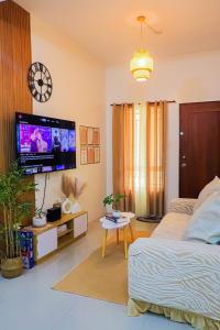 een slaapkamer met een bed en een flatscreen-tv bij Cozy Three-Bedroom Staycation House with Netflix, Wi-Fi, and Free Parking Garage near SM Caloocan in Manilla