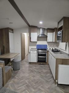 eine Küche mit einem Herd und einem Tisch darin in der Unterkunft Lovely 4 Berth Caravan With Free Wi-Fi At Harts Holiday Park, Kent Ref 74108B in Leysdown-on-Sea