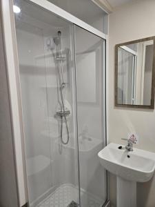 ein weißes Badezimmer mit Dusche und Waschbecken in der Unterkunft Lovely 4 Berth Caravan With Free Wi-Fi At Harts Holiday Park, Kent Ref 74108B in Leysdown-on-Sea