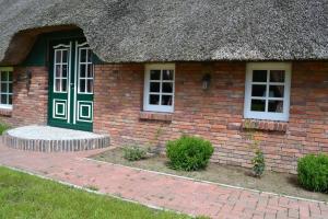 ein kleines Backsteinhaus mit Strohdach in der Unterkunft Ferienwohnung Süderfeld in Brake