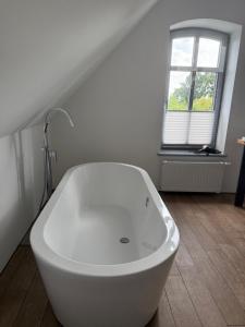 a white bath tub in a bathroom with a window at Edelhof1877 in Thedinghausen +16 photos