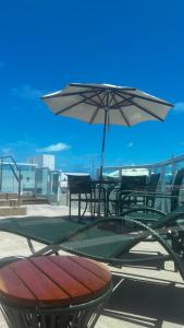 Una mesa y sillas con una sombrilla en un patio. en Flat com Hidromassagem Privativa no Centro De Porto de Galinhas - Sol e Mar Residence, en Porto de Galinhas