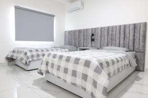 twee bedden in een witte kamer met een raam bij ريلاكس للأجنحة الفندقية in Amman