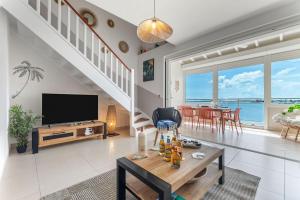 a living room with a television and a table at Tout est neuf dans ce beau Duplex pour 6 à 7p vue lagon in Marigot +28 photos