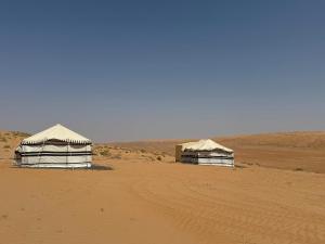 two tents in the desert with a dirt road at Sand Oasis camp in Al Ghabbī
