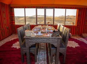 a dining room with a table and chairs and windows at Luxury Desert Queen Camp in Merzouga