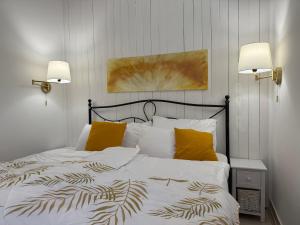 a bedroom with a bed with white sheets and yellow pillows at Haus Sonnenklang Sajkod in Tihany