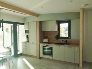 Una cocina con gabinetes blancos y un fregadero y una ventana. en O'Cocoon, en Fraize