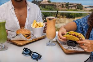 a man and woman sitting at a table with a sandwich and chips at Jupiter Marina Hotel - Couples & Spa in Portimão