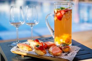 a tray of food with a drink and two wine glasses at Jupiter Marina Hotel - Couples & Spa in Portimão