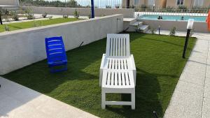 a white bench and a blue chair on the grass at AffittaSardegna - Bilo Elicriso in Trinità dʼAgultu