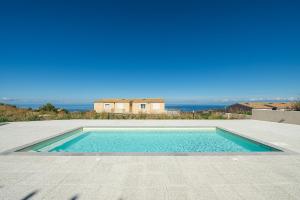 a swimming pool in front of a house with the ocean at AffittaSardegna - Bilo Elicriso in Trinità dʼAgultu