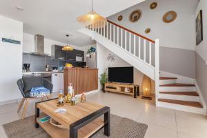 a living room with a table and a kitchen and stairs at Tout est neuf dans ce beau Duplex pour 6 à 7p vue lagon in Marigot