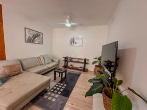 a living room with a couch and a flat screen tv at North Facing Seaside Apartment in Cronulla