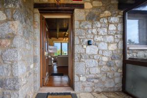 une porte ouverte menant à une maison en pierre avec un mur en pierre dans l'établissement Chalet Panorama -Three Level Escape in Parnassos, à Arachova