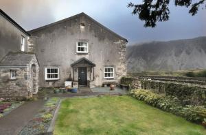 an old stone house with mountains in the background at The Screes Apartment - Short stroll from Wastwater in Nether Wasdale
