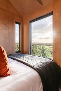 a bedroom with a bed with a large window at Cabins at Bogee Farm in Saint Ervan
