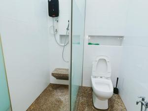 a bathroom with a toilet and a glass shower stall at Cozy Private Room for Relaxing Stays in Nibung Tebal +7 photos