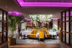 a restaurant with yellow chairs and tables and purple lighting at Wotton House in Dorking