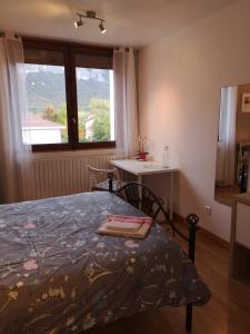a bedroom with a bed and a table and a window at Chambre chez l habitant in Crolles