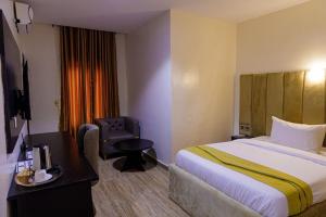 a hotel room with a bed and a chair at Vizit Hotel & Suites in Benin City +6 photos