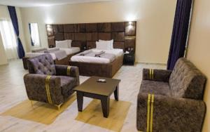 a hotel room with a bed and a couch and chairs at Vizit Hotel & Suites in Benin City