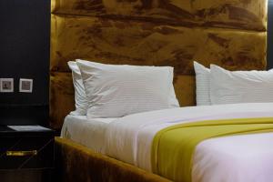 a bedroom with a bed with white sheets and pillows at Vizit Hotel & Suites in Benin City