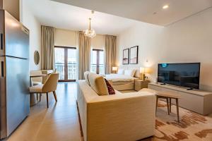 ein Wohnzimmer mit einer Couch und einem Bett und einem Fernseher in der Unterkunft F1 Lovers Escape Yas Golf Studio Near Yas Marina Circuit in Abu Dhabi