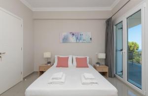 a white bedroom with a large bed with pink pillows at Demargia Villa A - First Floor Apartment in Áno Yerakaríon +30 photos