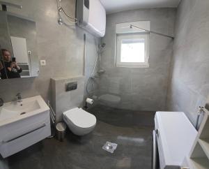 a bathroom with a toilet and a sink and a mirror at Apartman Bugi Vukovar in Vukovar +12 photos