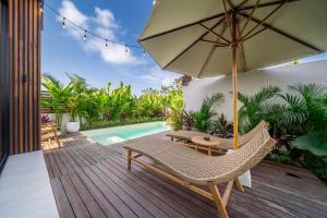 a deck with a chair and an umbrella and a pool at Oasis Pandawa 10A - Private Luxury Awaits - Newly Built Villa with Pool in Ungasan