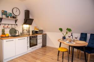 a kitchen with white cabinets and a table and blue chairs at Maya's Flats - Dluga 66 Attic Gdansk in Gdańsk
