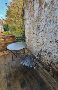a table and a chair next to a stone wall at Gîte a la source in Bergholtz-Zell