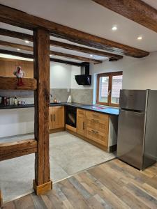 a kitchen with wooden cabinets and a stainless steel refrigerator at Gîte a la source in Bergholtz-Zell