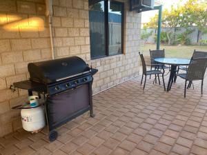 a grill on a patio with a table and chairs at Questro Lodge in Kalbarri
