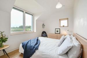 a white bedroom with a bed and two windows at Brook Lodge Farm in Isfield