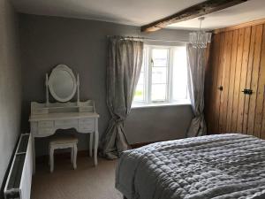 a bedroom with a bed and a mirror and a window at Cottage by the Castle grade II in Kenilworth