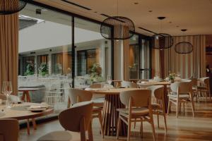a restaurant with white tables and chairs and windows at AMA Stay in San Vigilio Di Marebbe