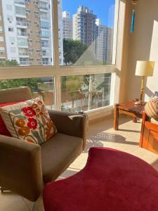 a living room with a couch and a large window at Ótimo AP 2 Dorm com suíte prox ao Consulado Americano in Porto Alegre